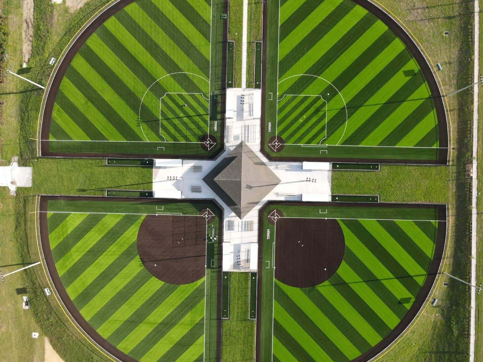 Top-down view of a four-field sports complex with turf infields