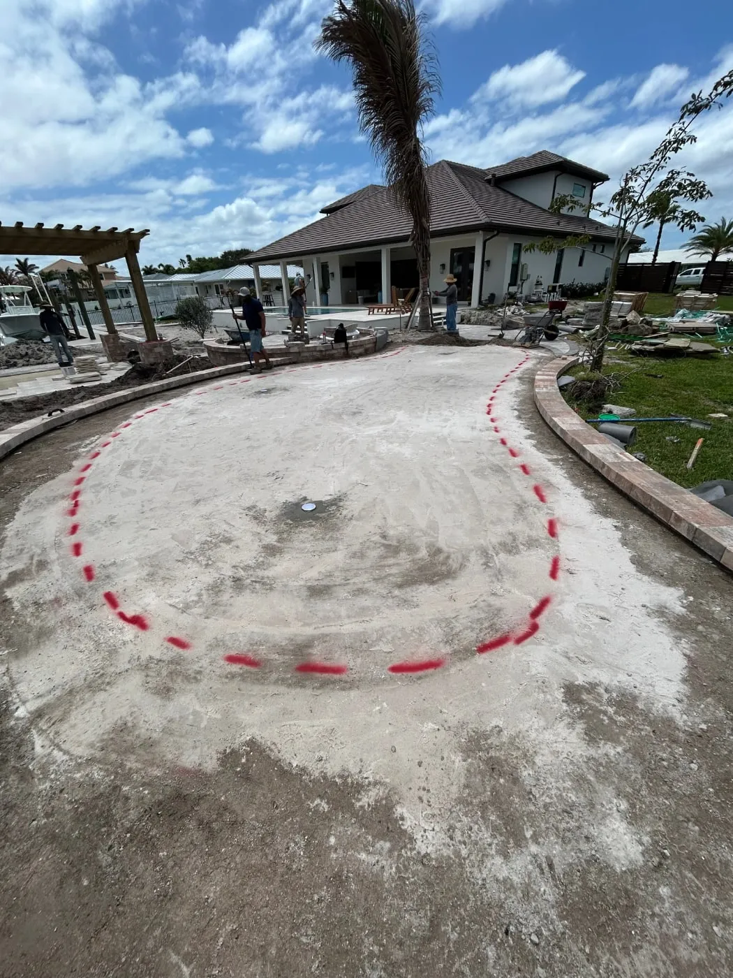 Compacted light-colored base inside a curved paver border, with the putting green outline marked in red paint
