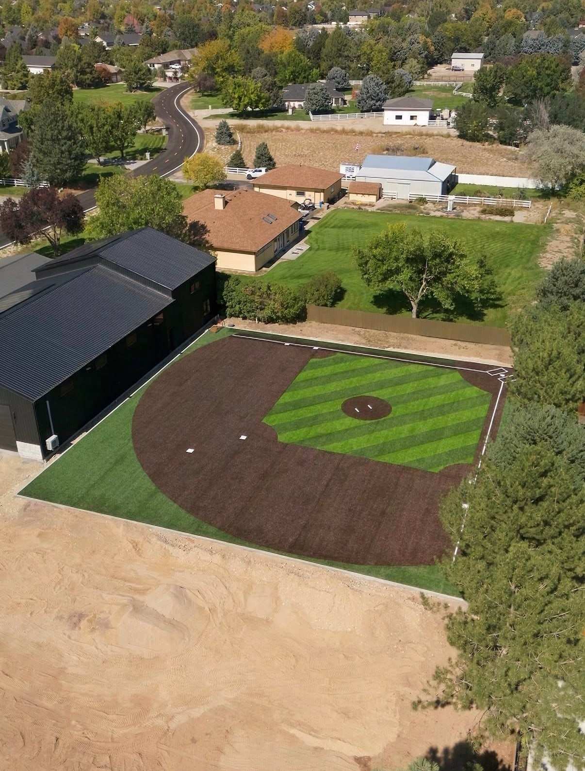 Aerial view of a private backyard ballfield with a striped turf outfield