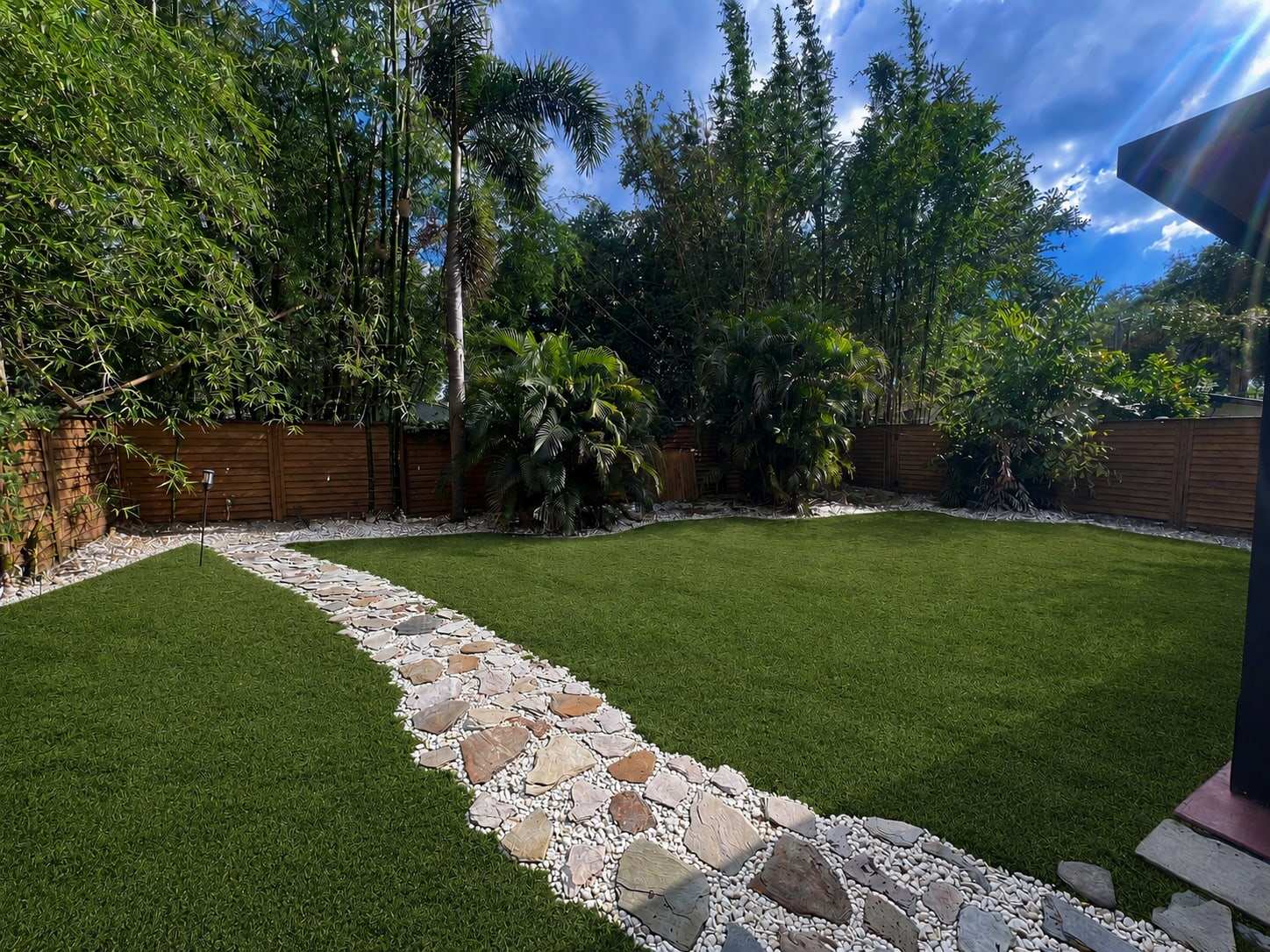 Backyard turf lawn split by a flagstone and gravel path