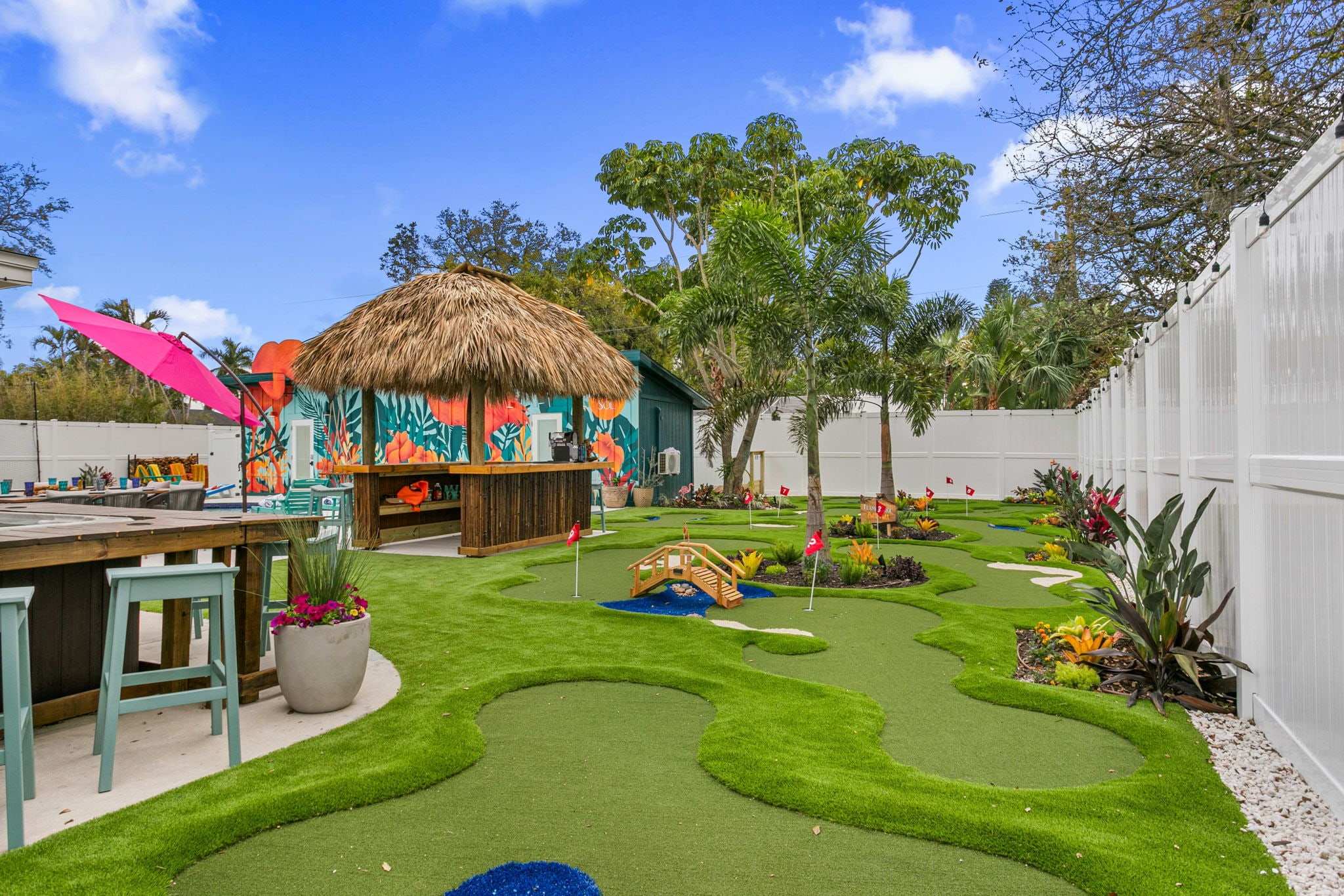 Curving turf putting course with flags beside a tiki hut