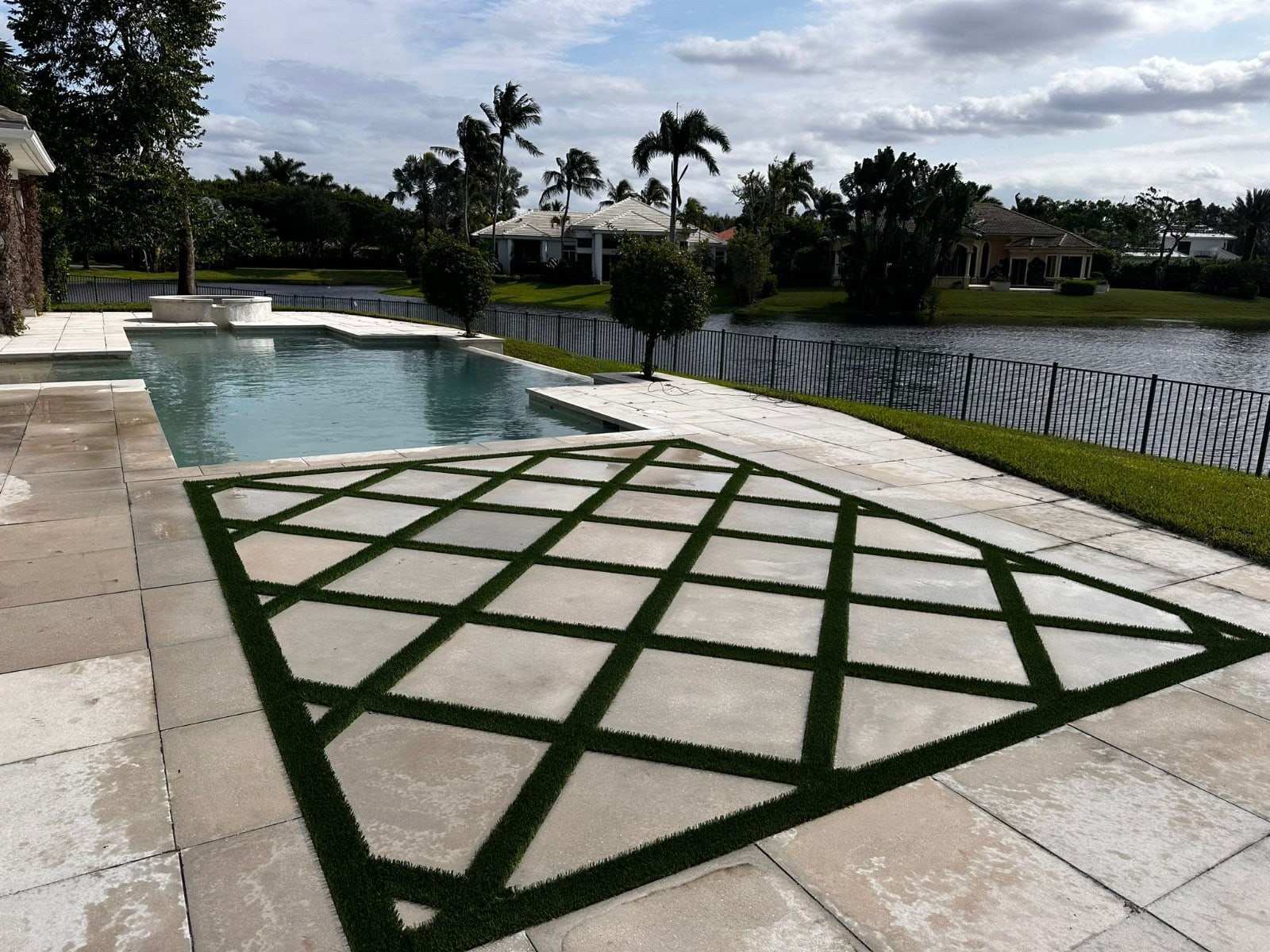 Pool deck with turf strips set in a diamond pattern between pavers