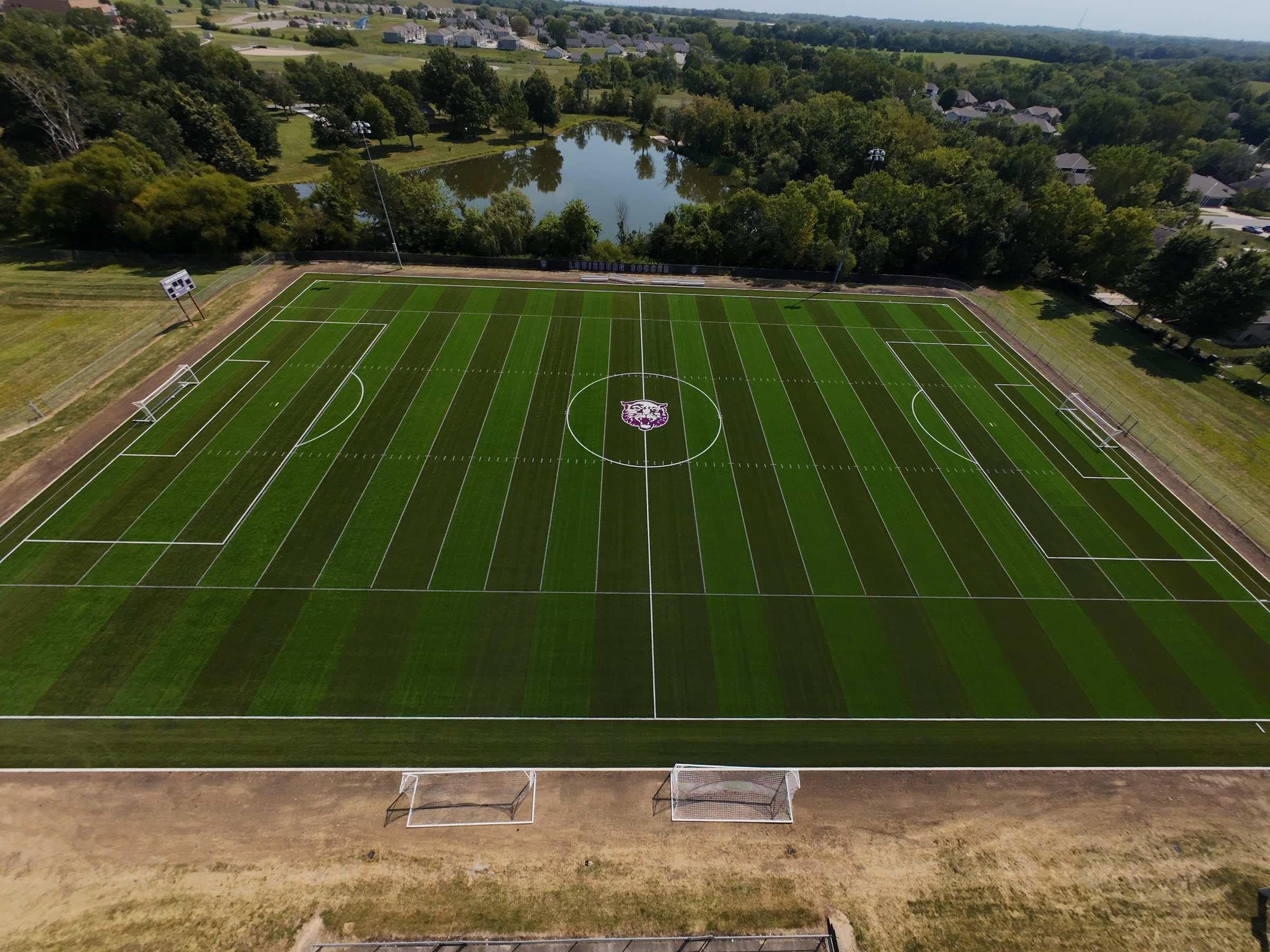 Striped turf soccer field beside a pond