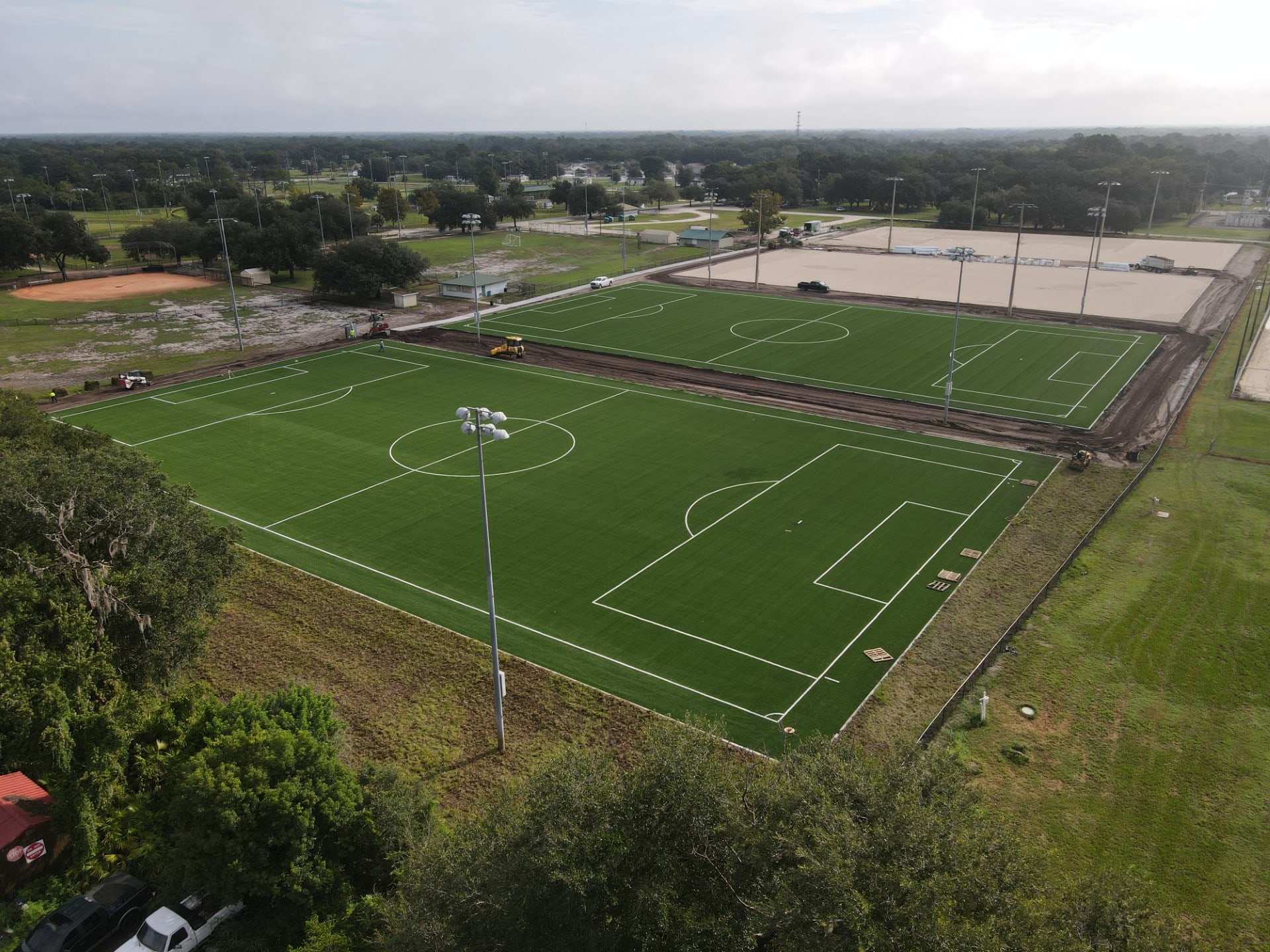 Two turf soccer fields with light poles in a park